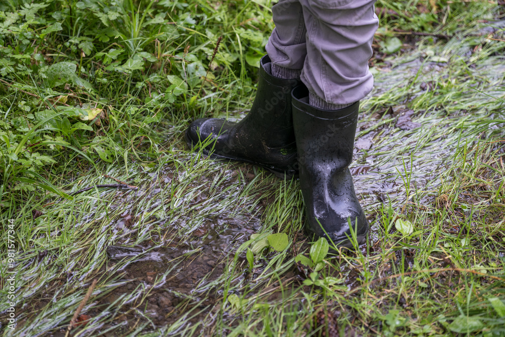 A child in black rubber boots brakes the water.
A child in black rubber boots brakes the water.