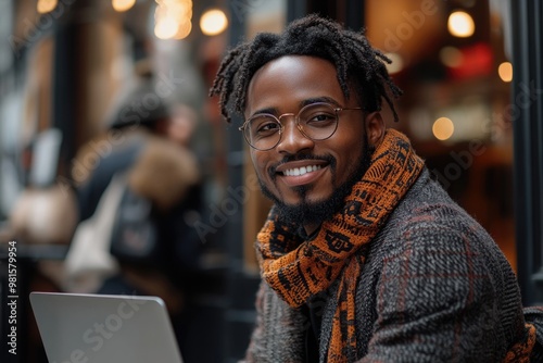 Smiling Black Businessman Using Laptop During Coffee Break in Modern Urban Cityscape photo