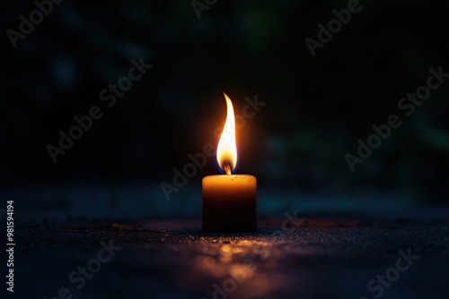 A solitary candle flickers softly in the darkness, creating a warm glow during a quiet evening moment