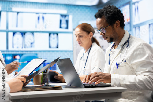 Doctor analyzing radiography and test results during meeting in a treatment center. Healthcare specialists collaborate on treatment plans and disease prevention, collective work and teamwork.