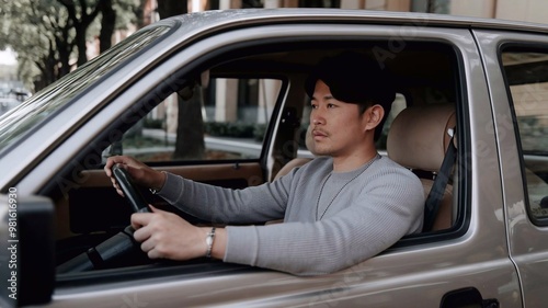 Portrait of a young Asian Japanese adult man driving a car with hands on the wheel