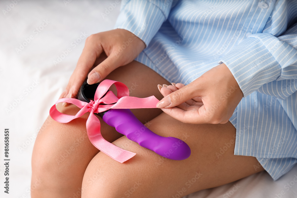 Young woman with gift vibrator sitting in bedroom, closeup Young woman with gift vibrator sitting in bedroom, closeup