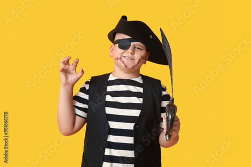 Slika na platnu Cute happy boy with sword dressed as pirate for Halloween party on yellow backgr