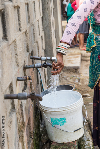 Filling a bucket with drinking water at a public tap. photo