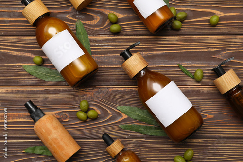 Composition with bottles of cosmetic products and green olives on wooden background