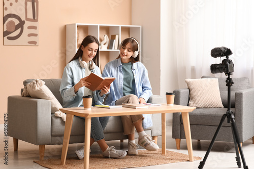 Young sisters in headphones with book recording podcast at home