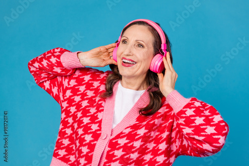 Photo portrait of nice pensioner female touch headphones listen music wear trendy pink print outfit isolated on blue color background photo