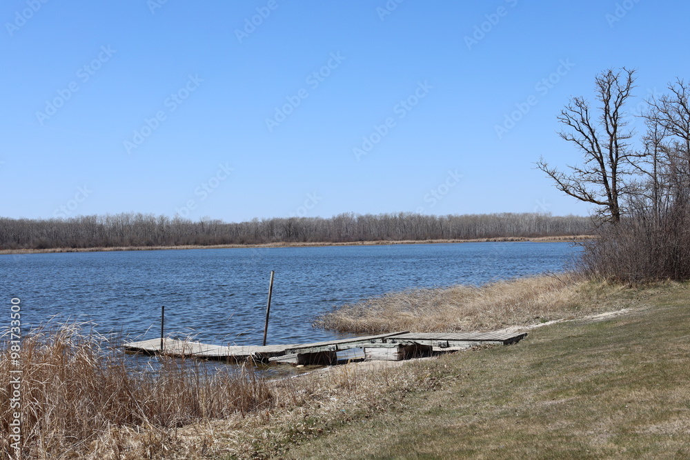 Fototapeta premium rustic wooden dock on a lake under blue skies