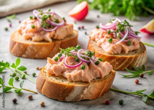 Smoked salmon pâté spread on toasted baguette slices, garnished with pickled red onion, capers, and microgreens, on a marble kitchen counter, against a soft, natural light