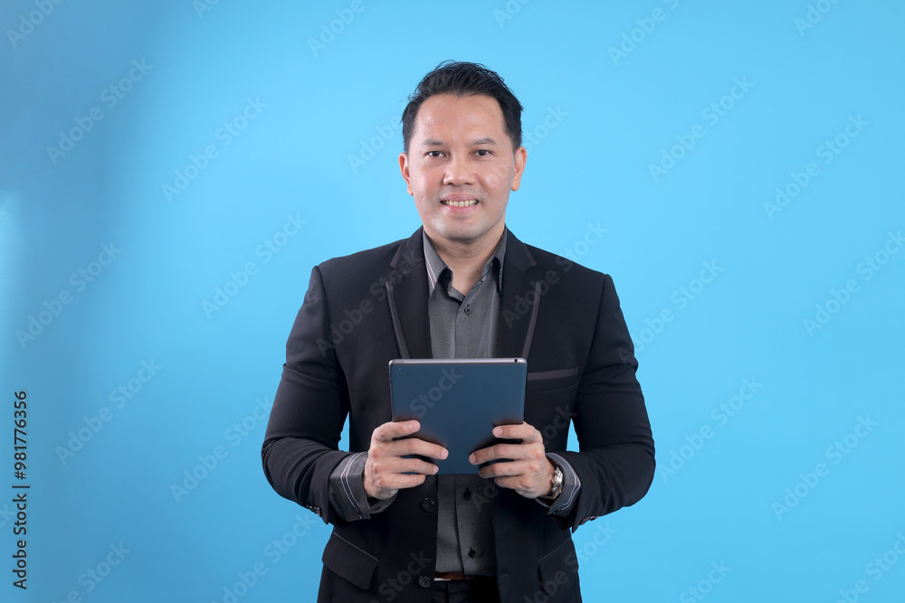 Happy Asian businessman using digital tablet isolated on blue background Happy Asian businessman using digital tablet isolated on blue background