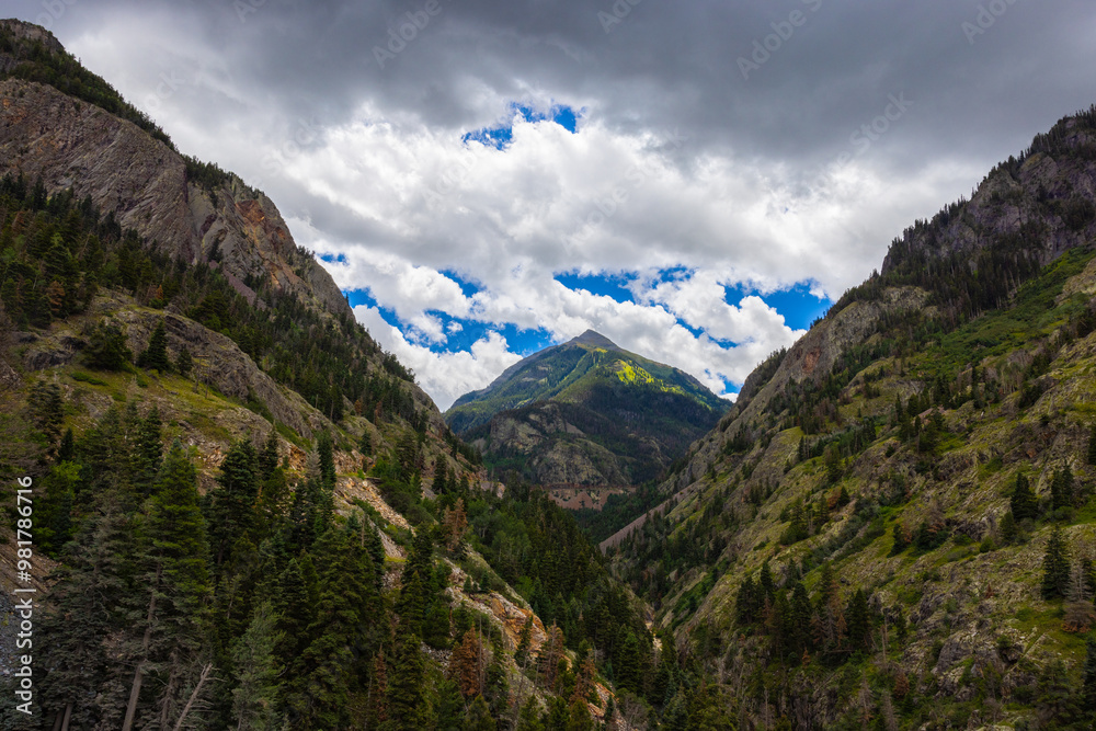Photograph of stormy cloudy bright blue sky picking throw Abrams Mountain in Colorado near bear creek park. Vivid bright landscape photo. Photograph of stormy cloudy bright blue sky picking throw Abrams Mountain in Colorado near bear creek park. Vivid bright landscape photo.