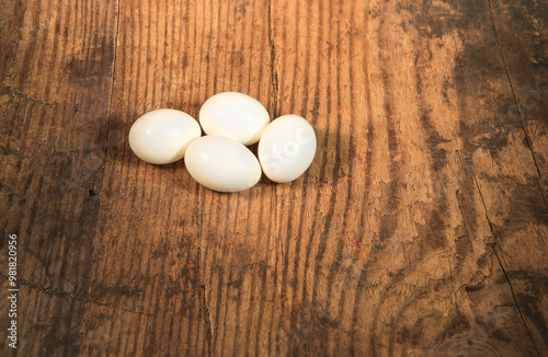 Peeled fresh organic eggs isolated on a rustic wooden table with advertising space.