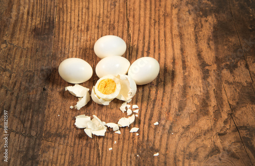 Peeled fresh organic eggs isolated on a rustic wooden table with advertising space.