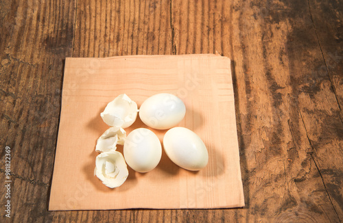 Peeled fresh organic eggs isolated on a rustic wooden table with advertising space.