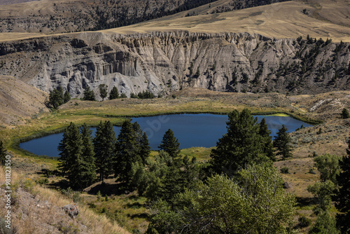 Landscape photograph of cliffs, hills, pine trees and small pound found at Yellowstone national park in Wyoming USA