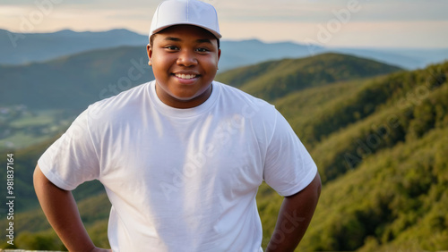 Plus size black teenage boy wearing white t-shirt and white baseball cap standing on a mountain