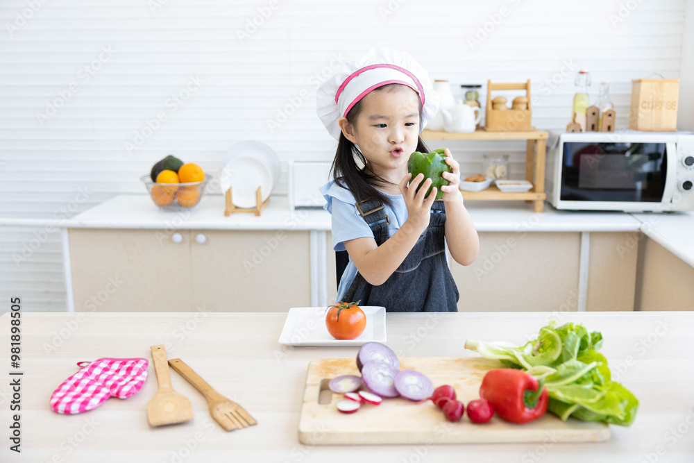 asian kid holding bell pepper and preparing vegetables meal in the kitchen asian kid holding bell pepper and preparing vegetables meal in the kitchen