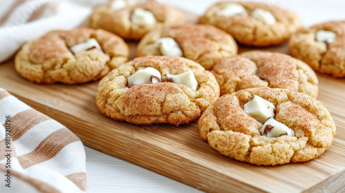 Freshly baked cookies with white and dark chocolate chunks on a wooden board, beautifully arranged with a kitchen towel