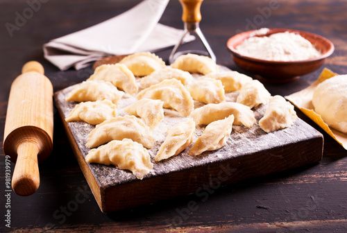 Raw Vareniks with potato filling on a wooden board / The concept is traditional Ukrainian cuisine. Horizontal orientation.