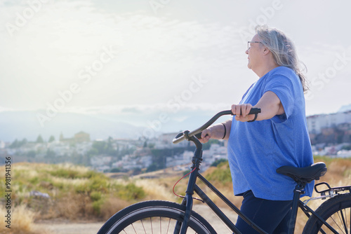 Photos an overweight mature woman rides a black retro-style bicycle against a cloudy mo