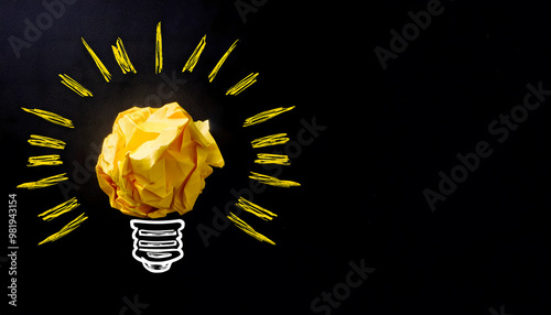 Yellow Crumpled paper as light bulb metaphor over black background with space for your text,  idea, inspiration, thinking, brainstorming concept
