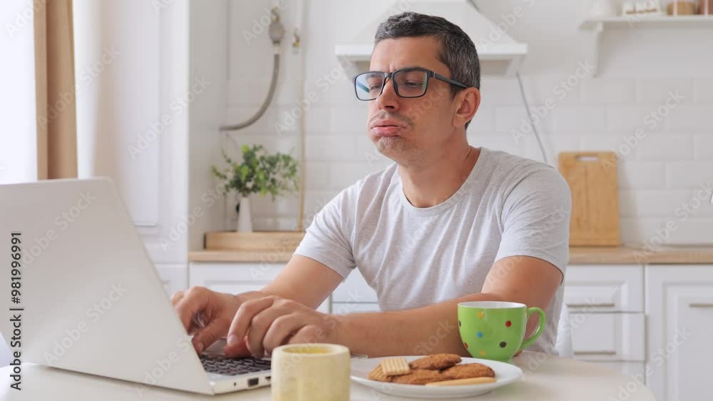 Despair man sitting at table in kitchen working on laptop angrily yelling at screen while browsing website frustrated by slow internet connection overwhelmed with remote job tasks Despair man sitting at table in kitchen working on laptop angrily yelling at screen while browsing website frustrated by slow internet connection overwhelmed with remote job tasks