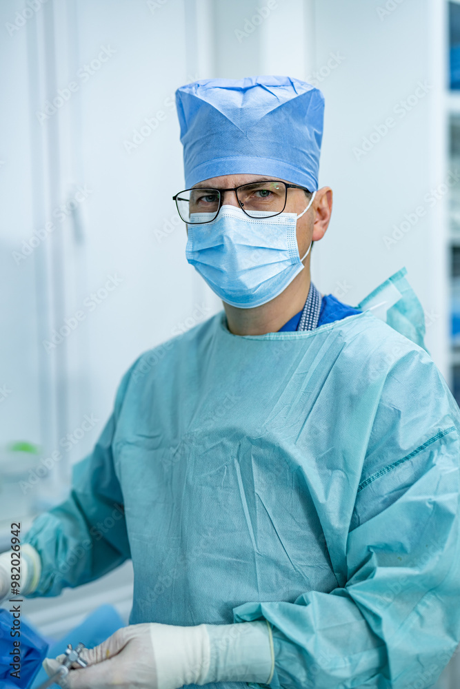 Surgeon readying for surgery in hospital. A surgeon dressed in scrubs and protective gear prepares surgical instruments in a well-equipped hospital operating room. Surgeon readying for surgery in hospital. A surgeon dressed in scrubs and protective gear prepares surgical instruments in a well-equipped hospital operating room.