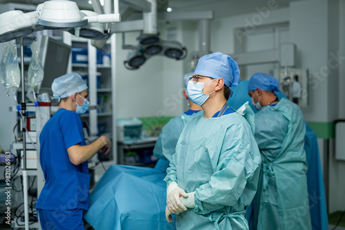 Surgical team readies for procedure. A surgical team in scrubs and masks is preparing for an operation in a modern hospital environment, focused and attentive to their tasks.