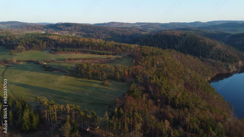 Flying above a forest with long shadows in sunset next to a reservoir Kamýk in Czechia Flying above a forest with long shadows in sunset next to a reservoir Kamýk in Czechia