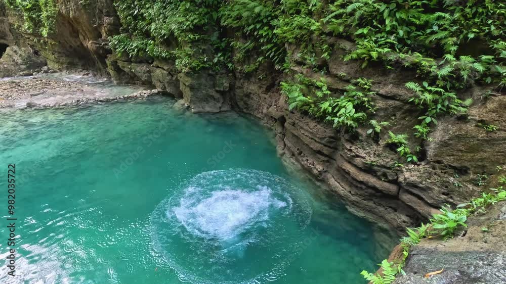 A man cliff jumps from a platform while canyoneering at Kawasan Falls in Cebu, Philippines. He runs and jumps from the platform down into the bright blue water below. A man cliff jumps from a platform while canyoneering at Kawasan Falls in Cebu, Philippines. He runs and jumps from the platform down into the bright blue water below.