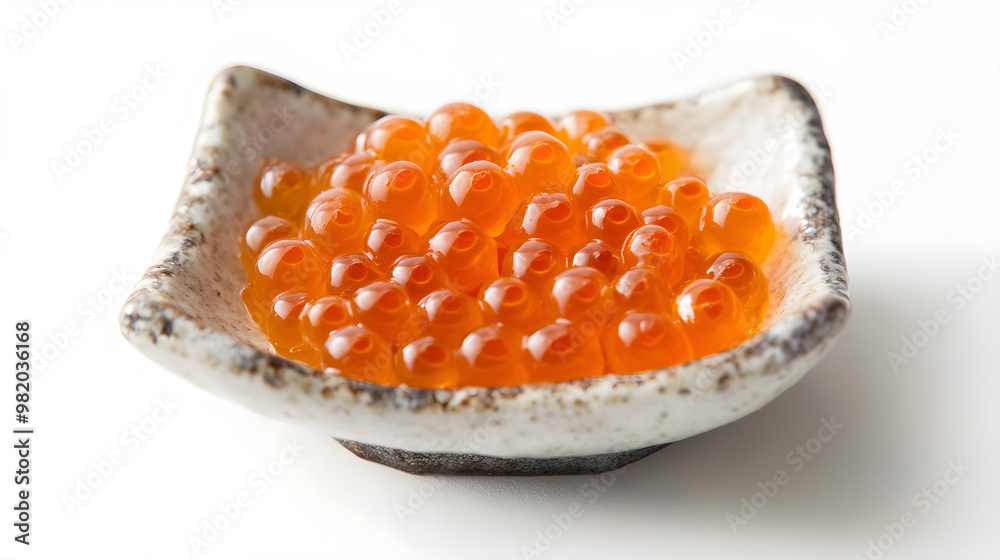 Close-up of salmon roe in a small dish, vibrant orange against the white Close-up of salmon roe in a small dish, vibrant orange against the white