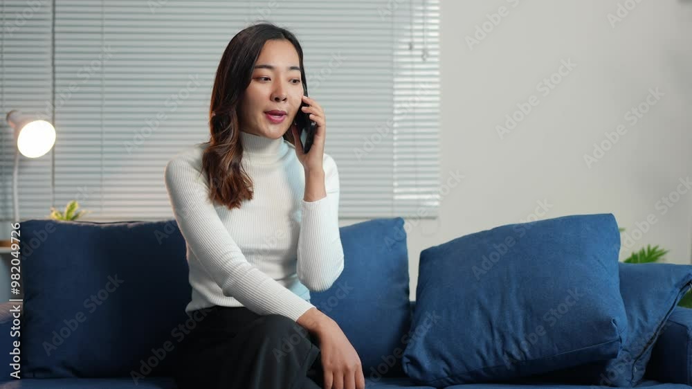 Happy Asian woman relaxing on sofa and playing with mobile phone. Attractive woman watching movie, chatting online with e-commerce shopping via mobile application at living room at home. Happy Asian woman relaxing on sofa and playing with mobile phone. Attractive woman watching movie, chatting online with e-commerce shopping via mobile application at living room at home.