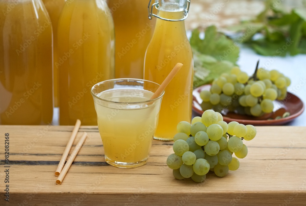 Fototapeta premium Homemade white grape syrup in bottles and grape juice in a glass. Made from fresh aromatic organic white grapes and honey or sugar.