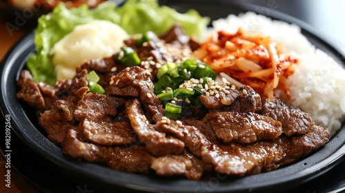 A delicious meal featuring marinated beef, rice, kimchi, and vegetables on a black plate.