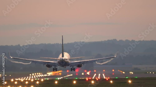 The plane lands at the airport. Commercial Jet Airplane Landing in airport runway at sunset. 
