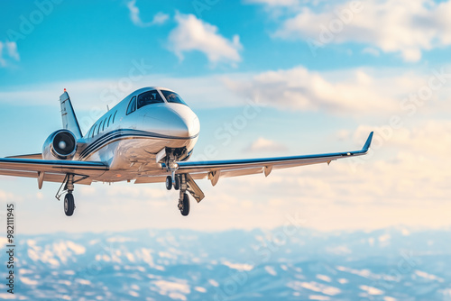 Private jet flying over snow-capped mountains on a sunny day