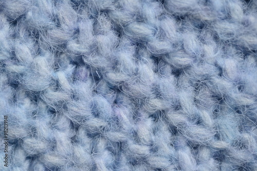 macro texture of woolen blue crocheted sweater as background, close-up of blue crocheted front surface, woolen texture of woolen wool, knitted front surface photo