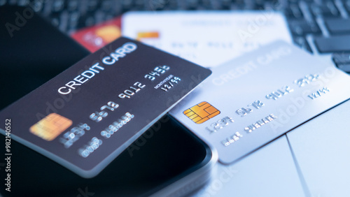 A collection of credit cards in different colors, on a laptop keyboard next to a smartphone. the concept of multiple payment options, digital banking, and secure online transactions in the financial.