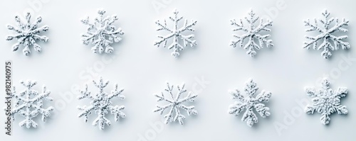 A collection of delicate white snowflakes arranged on a light background, showcasing unique shapes and intricate designs.