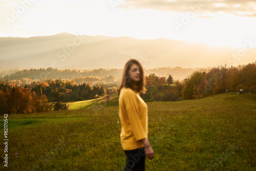 a portrait young woman in mustard sweater in autumn mountains at sunset