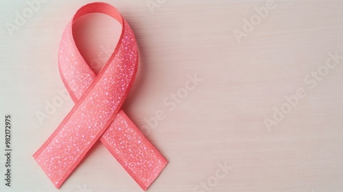 A colorful pink ribbon symbolizing support for breast cancer awareness on a wooden background. photo