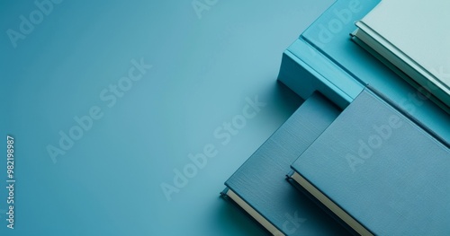 A variety of blue books of different shades are neatly arranged in a flat layout against a matching blue background, creating a harmonious scene.