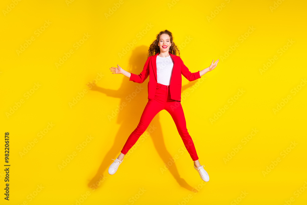 Full size photo of pretty young woman jump wear red suit isolated on yellow color background Full size photo of pretty young woman jump wear red suit isolated on yellow color background