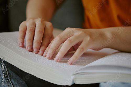 Medium close up of unrecognizable female hands touching Braille books page