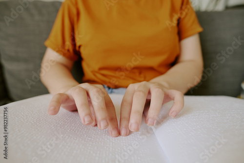 Tableau sur toile Unrecognizable female hands touching white page with Braille tactile system