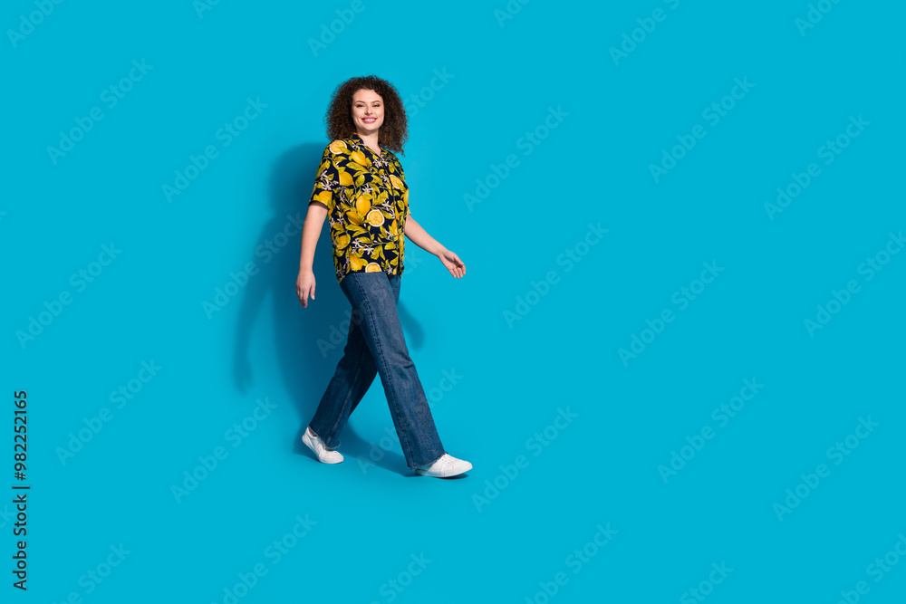Full length photo of charming positive woman wear print shirt smiling walking empty space isolated blue color background Full length photo of charming positive woman wear print shirt smiling walking empty space isolated blue color background