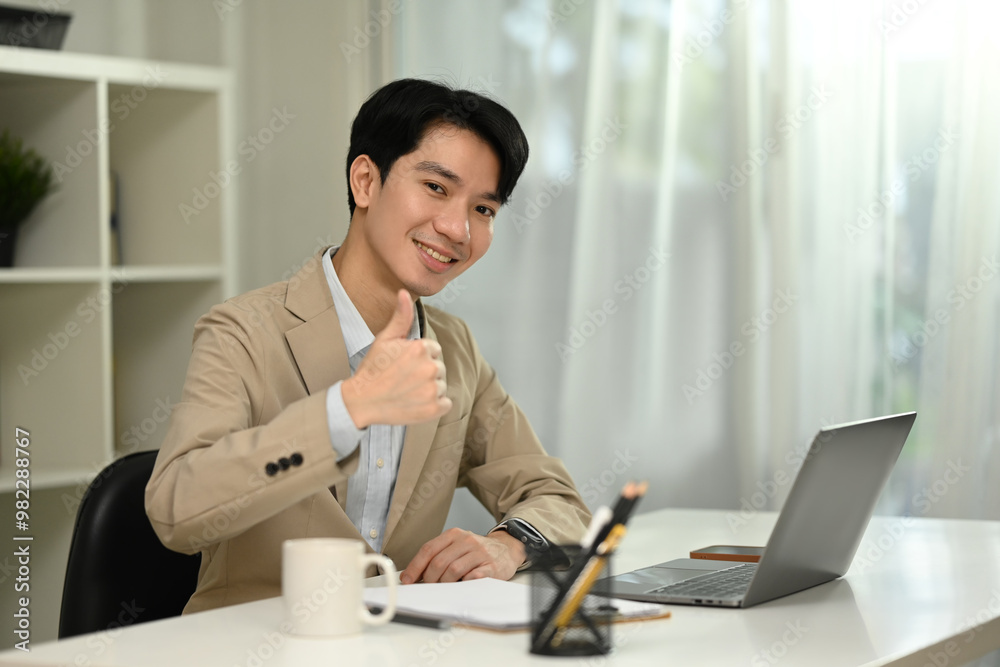 Professional businessman sitting at office desk and showing a thumbs up gesture Professional businessman sitting at office desk and showing a thumbs up gesture
