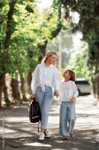 Holding the hands. Schoolgirl with her mother are outdoors together