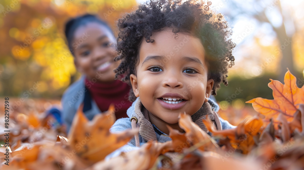 Mom and son happily play in autumn fallen leaves in sunny park Mom and son happily play in autumn fallen leaves in sunny park