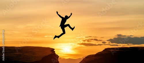 Silhouette of a man jumping over a gap with sunset in the background